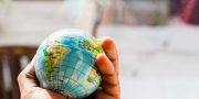A hand holding a small globe with geographical details visible.